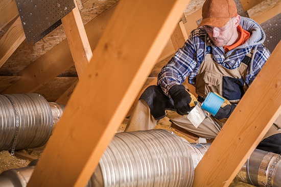 An HVAC contractor installing ductwork in a residential attic