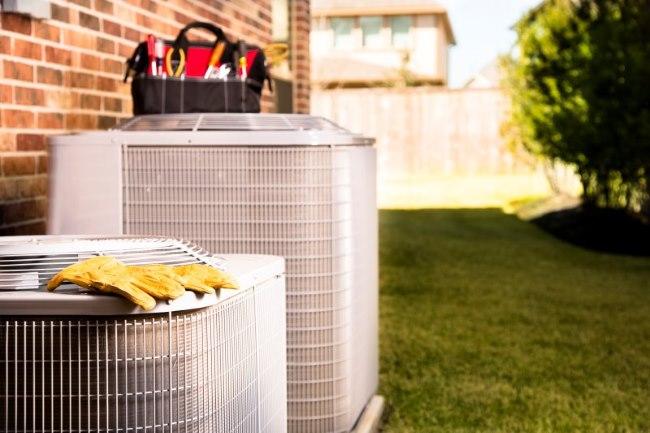 a pair of leather gloves and a tool bag on top of an air conditioner undergoing repair